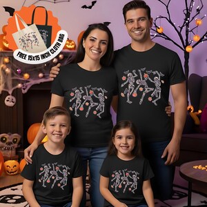 May include: A family of four wearing black t-shirts featuring a skeleton design with bats and pumpkins. A free 38x38 cm cloth bag with the same design is also shown.