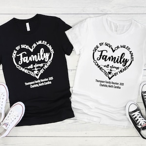 May include: A black t-shirt and a white t-shirt, each featuring a heart-shaped graphic with the text "Side by side or miles apart, Family will always be connected by heart" and "Thompson Family Reunion 2025, Charlotte, North Carolina".