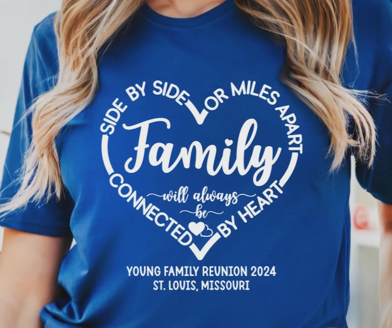 May include: A royal blue short-sleeved t-shirt featuring a white heart-shaped graphic with the text "SIDE BY SIDE OR MILES APART FAMILY WILL ALWAYS BE CONNECTED BY HEART" and "YOUNG FAMILY REUNION 2024 ST. LOUIS, MISSOURI" printed in white lettering.