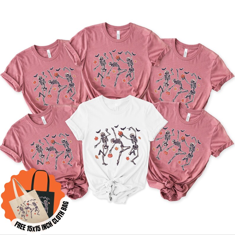 May include: Six t-shirts, five in a dusty rose hue and one white, are displayed. Each shirt has a dancing skeleton design with pumpkins, bats, and leaves, ideal for Halloween. A free 38x38 cm cloth bag is included.