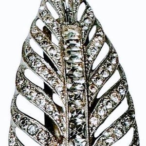 May include: A silver leaf-shaped brooch with a central design of clear rhinestones and smaller rhinestones outlining the leaf shape.