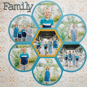 May include: A scrapbook page with the word "Family" in brown letters. The page features a flower-like design with photos of children in blue and white outfits. The photos are set against a backdrop of a bridge and a lake.
