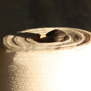 May include: A roll of white paper towels on a metal holder with a black knob.