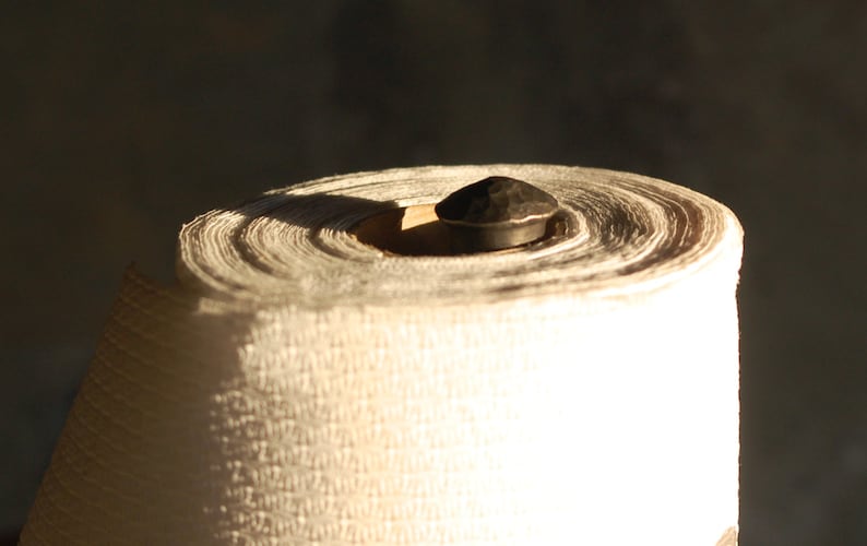 May include: A roll of white paper towels on a metal holder with a black knob.