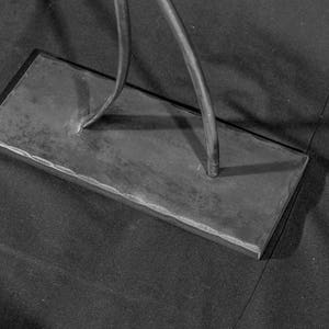 May include: A black metal base with a textured surface. Two metal rods are attached to the base.