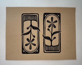 Pode incluir: Uma impressão botânica em preto e branco em papel castanho. A impressão apresenta duas molduras retangulares, cada uma contendo um design floral estilizado com folhas e flores. As molduras têm bordas decorativas e linhas verticais.