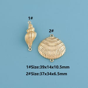 May include: Two gold-colored seashell charms. One is a spiral conch shell, and the other is a fan-shaped scallop shell. The text indicates the sizes: 1# is 1.54 x 0.55 x 0.41 inches, and 2# is 1.46 x 1.34 x 0.26 inches.