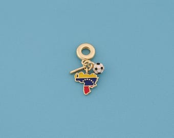 May include: Gold-colored charm featuring a soccer ball and a map of Venezuela with the country's flag colors. The charm has a loop for attaching to a bracelet or necklace. The background is a solid light blue.
