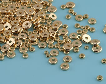 May include: A collection of small, gold-colored metal beads with a circular shape and a hole in the center. The beads are scattered on a light blue surface, varying in size.