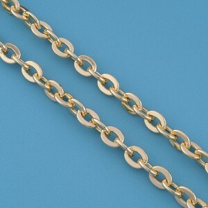 May include: A gold-toned metal chain necklace featuring a series of uniform, oval-shaped interlocking links. The chain has a polished, reflective surface that catches the light, creating a consistent and repeating pattern throughout the entire length.