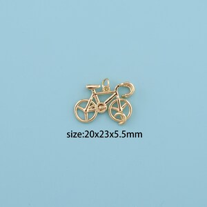 May include: A gold-colored bicycle charm with a detailed design. The charm measures 20mm x 23mm x 5.5mm. The image is set against a light blue background. The text "size:20x23x5.5mm" is visible.