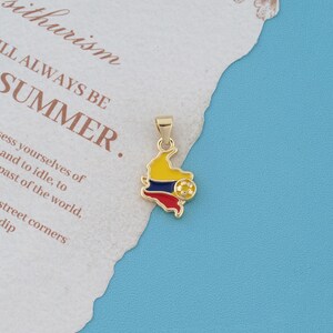May include: A gold-toned metal pendant shaped like the map of Colombia, featuring enamel fill in yellow, blue, and red horizontal stripes. A small, circular gold-toned soccer ball emblem is attached to the right side of the map-shaped pendant.