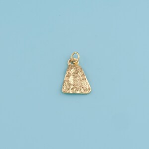 May include: A gold-colored pendant with a textured surface and a triangular shape. The pendant has a small loop at the top for attaching to a chain. The background is a solid light blue.