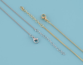 May include: Close-up of several necklace chains in silver and gold tones. The chains have different styles, including curb chains and chains with extender links and lobster clasps. The background is a solid light blue.