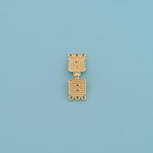 Op de afbeelding: Een goudkleurig sieradenonderdeel met twee vierkante secties verbonden door een klein scharnier. Elke vierkant heeft een textuurpatroon en kleine lussen aan de boven- en onderkant, tegen een lichtblauwe achtergrond.