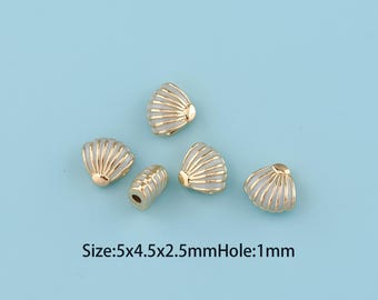 May include: Five small shell-shaped beads with a gold-tone metal frame and white enamel inlay. The beads measure 5x4.5x2.5mm with a 1mm hole. The design features raised gold ridges over a smooth white surface, mimicking the appearance of a seashell.