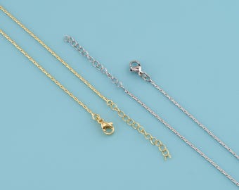 May include: Three delicate necklaces in gold, silver, and gold-toned finishes. Each chain features a lobster clasp and an extender chain. The necklaces are presented against a light blue backdrop.