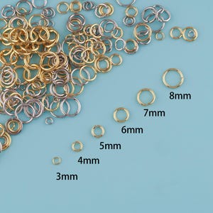May include: A collection of gold-colored and silver-colored jump rings in various sizes. The image shows jump rings ranging from 3mm to 8mm in diameter. The sizes are labeled in millimeters. These rings are commonly used in jewelry making and crafts.