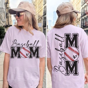 May include: Light purple t-shirt with the words "Baseball MOM" in black and a baseball graphic. The back of the shirt also features the words "Baseball" and "MOM" with a baseball graphic. The shirt is a comfortable, casual style.