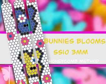 May include: Three pens with white honeycomb patterns and colorful floral designs. The pens have silver tips and are decorated with pink, blue, black, and yellow accents. The text "Bunnies Blooms" and "SSIO 3MM" is visible.