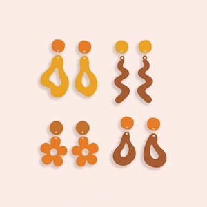 May include: Four pairs of earrings in different designs and colours. The earrings feature abstract shapes, wavy lines, and flower designs. The colours are orange, yellow, and brown, set against a light peach background. These earrings are a fashionable accessory.