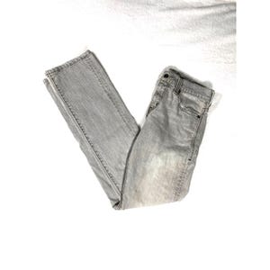 May include: Light gray denim jeans, folded and laid flat. The jeans have a classic five-pocket design, a button and zipper closure, and belt loops. The fabric appears to be a medium weight denim.