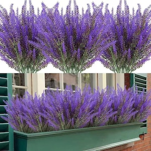 Peut inclure: Des tiges de lavande artificielle dans des tons de violet et de vert. La fausse lavande est disposée en bouquets, certains étant présentés dans un bac à fleurs vert. L'image montre un gros plan de la lavande, soulignant la texture et la couleur.