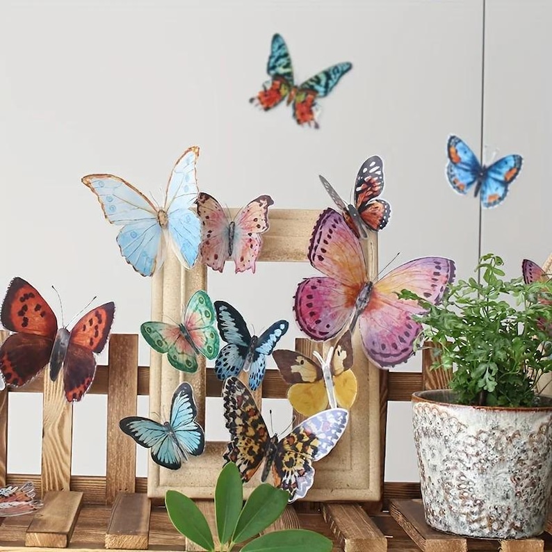 May include: A collection of colorful butterfly decorations in various sizes and patterns. The butterflies are in shades of blue, orange, pink, and green, some with intricate wing designs. They are arranged on a wooden frame and a wooden structure, creating a whimsical display.