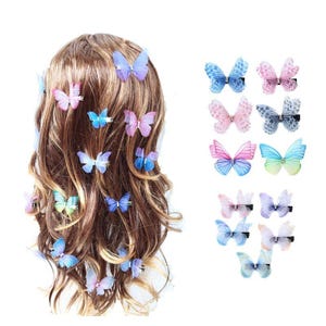 May include: A collection of butterfly hair clips in various colors, including blue, pink, and purple. Some clips are attached to brown hair, while others are displayed separately. The butterfly clips are made of a sheer material.