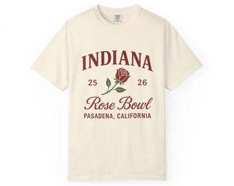 May include: Cream-colored t-shirt with a maroon graphic. The graphic reads "INDIANA" above a rose illustration, with "25 26" on either side. Below, it says "Rose Bowl" and "PASADENA, CALIFORNIA".