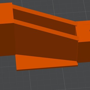 Puede incluir: Objeto naranja impreso en 3D con un diseño geométrico. El objeto tiene dos bloques rectangulares conectados por una sección inclinada con dos soportes paralelos. Cada bloque tiene un agujero circular.