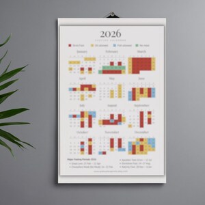 May include: A 2026 fasting calendar, displayed on a white poster. The calendar features color-coded blocks indicating fasting periods, with text at the top and bottom. The poster is hanging on a wall.