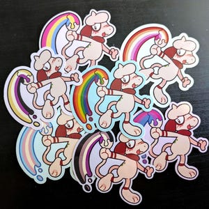 Könnte beinhalten: Eine Sammlung von gestanzten Aufklebern, die eine Zeichentrickfigur mit Baskenmütze und Schal zeigen, die einen Pinsel hält, der bunte Farbspuren hinterlässt, darunter Regenbogen- und Flaggenmuster, mit hellem Körper und roten Ohren.