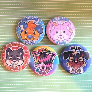 May include: Five circular pin-back buttons featuring cartoon animal illustrations. The buttons display the text SQUEAKY FUR, PLUSHIE FUR, HUNGRY FUR, PLUR FUR, and PUP FUR, each accompanied by colorful, stylized animal character faces.