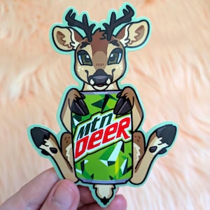 May include: A die-cut sticker featuring a cartoon deer with brown fur and dark antlers, holding a green soda can with the text mtn deer printed in white and red letters. The sticker has a light mint green border and a white outline.