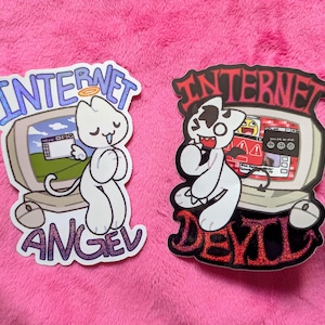 Könnte beinhalten: Zwei Aufkleber mit Cartoon-Katzen mit Computermonitoren. Einer trägt die Aufschrift "Internet Angel" mit einer Katze mit Heiligenschein. Der andere trägt die Aufschrift "Internet Devil" mit einer Katze mit Hörnern und Schwanz.