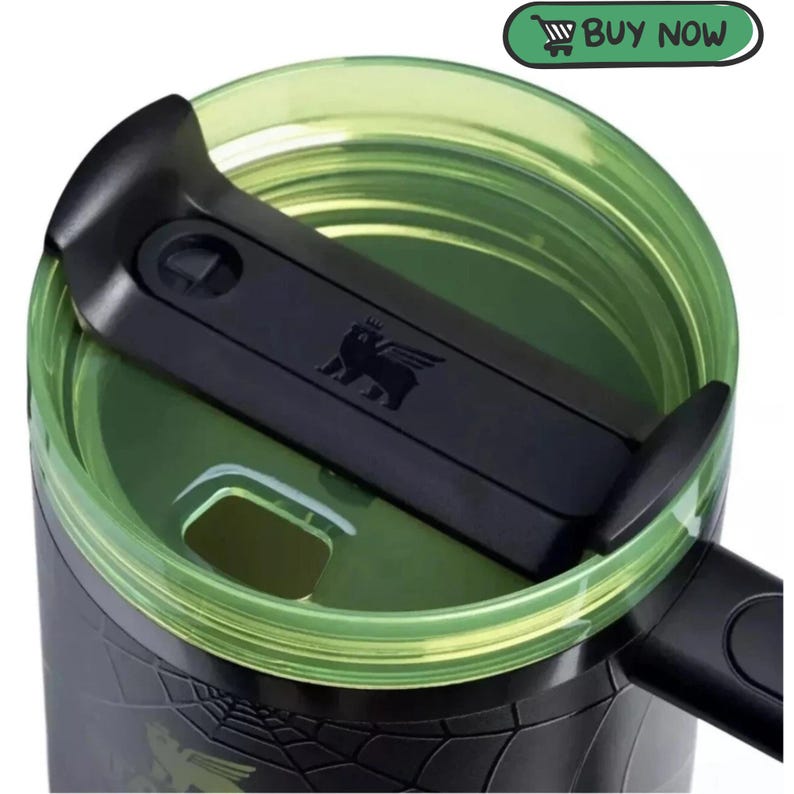 May include: A black travel mug with a translucent lime green lid and a black sliding closure mechanism. The lid features a small embossed winged lion logo. A green button with a shopping cart icon and the text BUY NOW is visible.