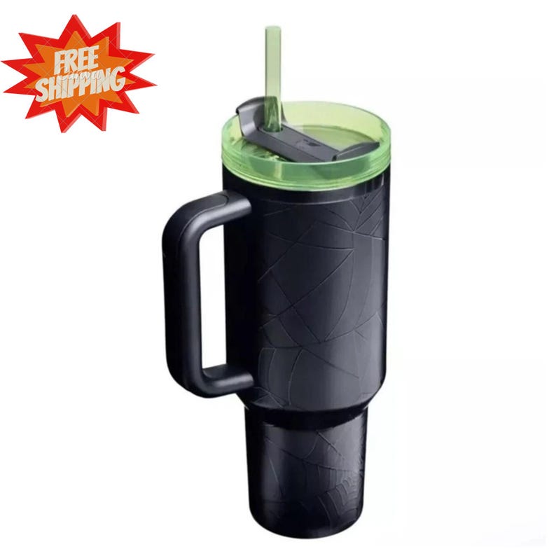 May include: A matte black tumbler with a handle and a translucent lime green lid featuring a matching straw. The exterior of the tumbler is embossed with a subtle, geometric spiderweb pattern that wraps around the entire cylindrical body.