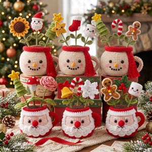 May include: A collection of six crocheted mugs featuring snowman and Santa Claus faces, each holding various festive toppers like a sunflower, candy cane, gingerbread man, Christmas tree, snowflake, bell, and mushroom on green stems.