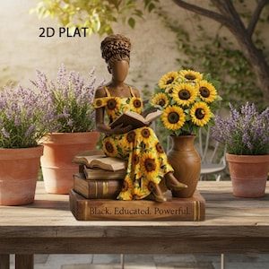 May include: A decorative statue of a woman in a yellow sunflower print dress, seated on books, reading. The statue is on a wooden table with potted plants and sunflowers in a vase. The text on the books reads: Black. Educated. Powerful.