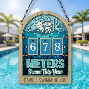 May include: Wooden swimming log with a blue and white design. The sign features the numbers 678, the words "METERS Swam This Year", and a diving mask and flippers graphic. The text "DAVID'S SWIMMING LOG" is at the bottom.
