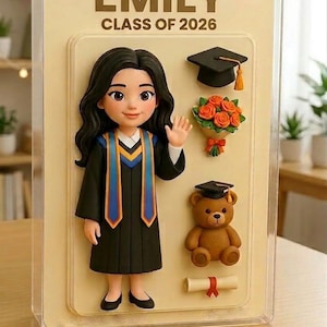 Puede incluir: Una exhibición temática de graduación con el nombre "EMILY" y "CLASS OF 2026". Presenta una figura de graduada con una toga negra con detalles azules y dorados, un birrete, un ramo de rosas, un oso de peluche y un diploma.