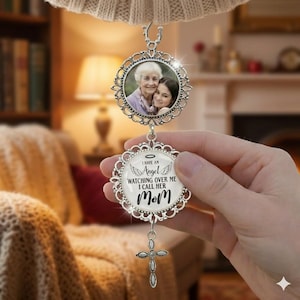 May include: A silver-colored memorial ornament with a photo of two people in an ornate frame. Below, a circular pendant reads "I have an Angel watching over me I call her Mom" with a cross charm.