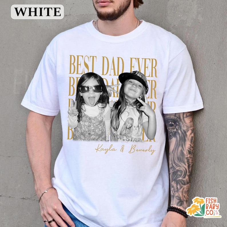 Puede incluir: Camiseta blanca con el texto dorado "BEST DAD EVER". La camiseta presenta una foto en blanco y negro de dos ni&ntilde;as, con los nombres "Kayla & Beverly" debajo. La camiseta tiene cuello redondo.