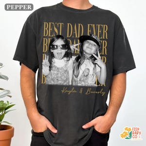 Puede incluir: Camiseta negra con un dise&ntilde;o de texto dorado que dice "BEST DAD EVER" y presenta una foto en blanco y negro de dos ni&ntilde;as. Los nombres "Kayla & Beverly" est&aacute;n impresos debajo de la foto.