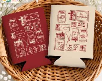 May include: Two beverage can coolers with a matchbox theme. One is burgundy, the other is cream. Each features matchbox illustrations and text that reads "Mia's bachelorette," "A match made in heaven," and "Nashville TN."