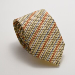 May include: A yellow silk tie with a pattern of small, colorful, overlapping scales. The tie is rolled up and ready to be worn.