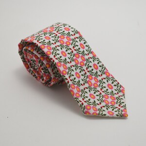May include: A white necktie with a pink and green floral pattern.
