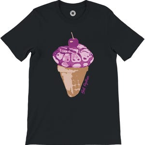 K&ouml;nnte beinhalten: Schwarzes T-Shirt mit einer skurrilen Illustration eines Eiswaffel. Das Eis ist lila mit einer Kirsche, und die Waffel ist hellbraun. Der Text "Ball Python" ist kursiv geschrieben. Ein lustiges und originelles Design.
