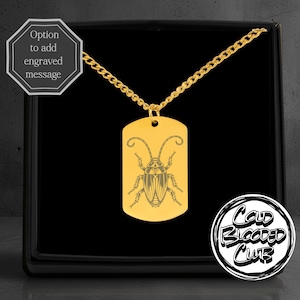 May include: Gold-colored dog tag pendant necklace with a detailed engraved cockroach design. The necklace is displayed in a black box. The text "Cold Blooded Club" is in a circular logo. The text "Option to add engraved message" is also visible.